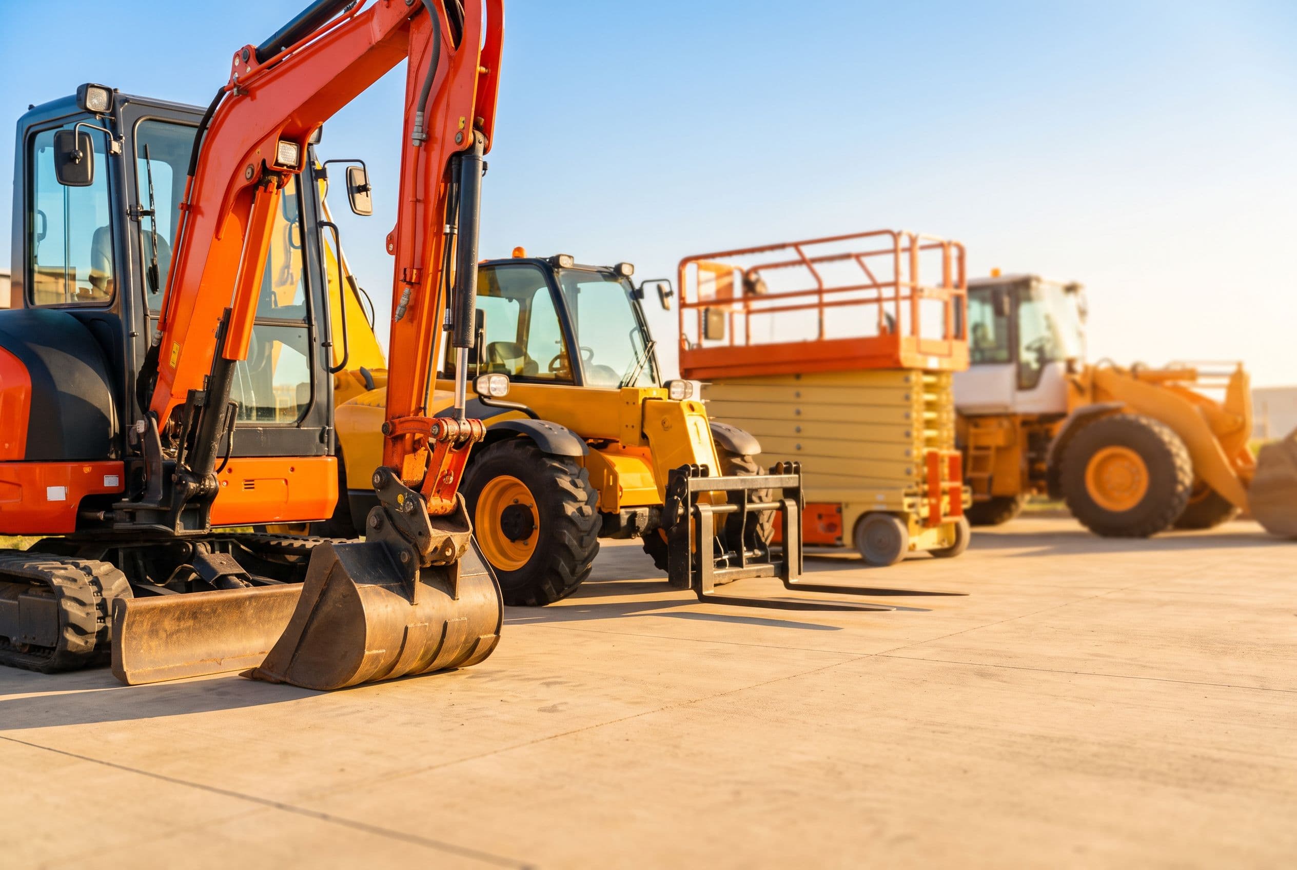 Rental machines lined up close together on clean concrete in a bright yard.